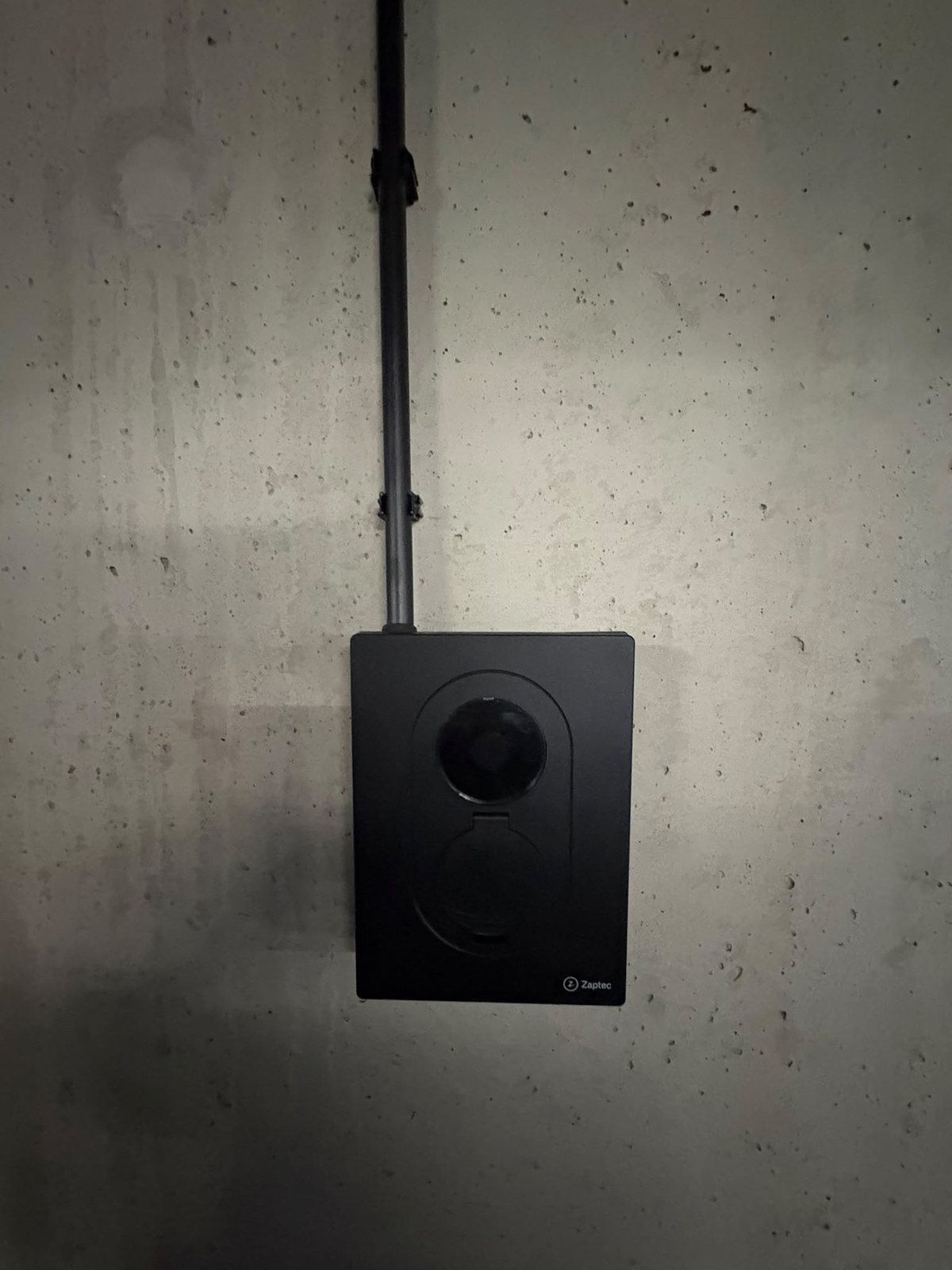 Zwarte Zaptec Go 2 laadpaal aan een betonnen wand in een parkeergarage in Amsterdam