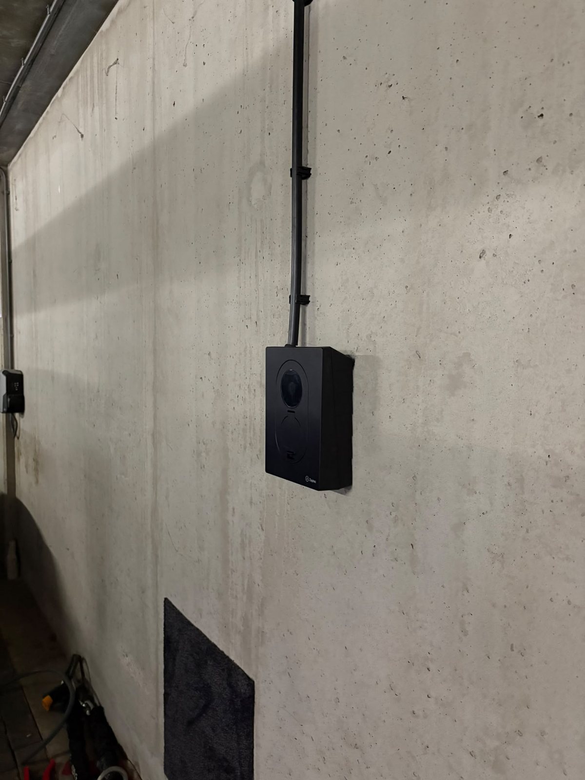 Zaptec Go 2 van opzij, met de kabelbuis langs de betonnen wand